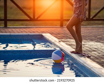 Fat Tanned Happy Girl With Dark Hair Braided In Bun In Bright Summer Suit Is Playing Near Pool With Inflatable Ball, Against The Background Of Golden Summer Evening Sun