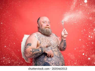 Fat thoughtful man with beard ,tattoos and wings acts like an magic fairy