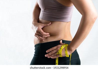 fat woman, fat belly, chubby, obese woman hand pinching on her excessive belly fat waist with measure tape, woman diet lifestyle concept - rear view - Shutterstock ID 1921298954