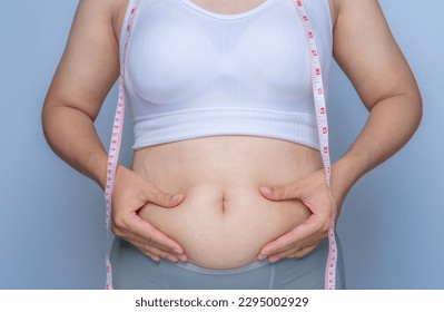 Fat woman, fat belly, obese, with both hands holding excess fat in her waist area, water obesity Overweight. Diabetes. Fitness. Abdomen. Adult background, health care concept.
