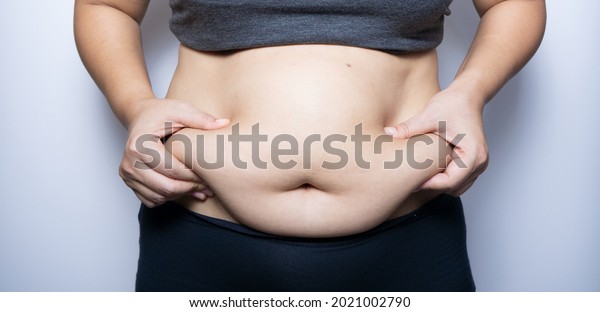 Fat\
woman hand holding fat belly on white\
background.
