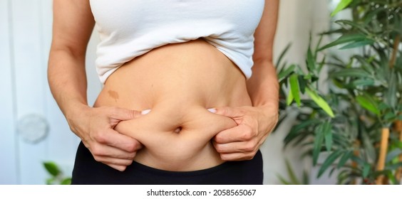 A fat woman holds folds of fat on her stomach in her hands. Starting a diet, proper nutrition, measuring body volume before weight loss. Healthy lifestyle concept