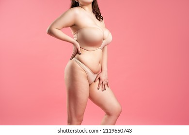 Fat woman with large breasts in a push-up bra on pink background, overweight female body, studio shot