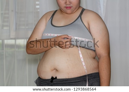 Fat woman measuring her breasts