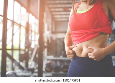 Fat woman, Obese woman hand holding excessive belly fat isolated on gym background, Overweight fatty belly of woman, Woman diet lifestyle concept to reduce belly and shape up healthy stomach muscle.
