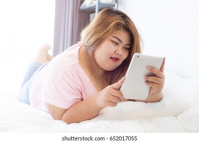 Fat Woman Using Smart Phone And Tablet On Bed, Person Using Digital Tablet In Living Room, Typing On A Tablet, Relaxing With Ipad. Girl Holding Tablet In Living Room. Overweight, Plus Size. Holiday.