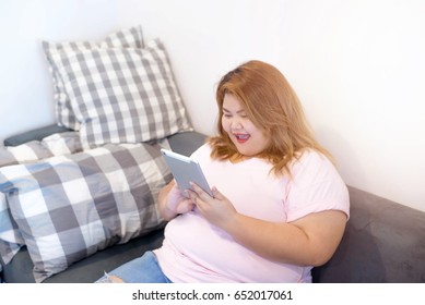 Fat Woman Using Smart Phone And Tablet On The Sofa, Person Using Digital Tablet In Living Room, Typing On A Tablet, Relaxing With Ipad. Girl Holding Tablet In Living Room. Overweight, Plus Size.