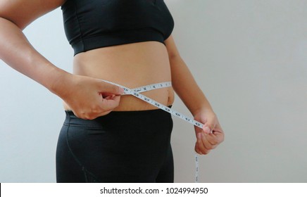Fat woman is using a fat tape measure on her stomach. - Shutterstock ID 1024994950