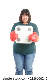 Fat woman wearing red boxing gloves She stood holding a weighing scale. standing on a white background. The concept of being overweight. Exercise to lose weight. white background