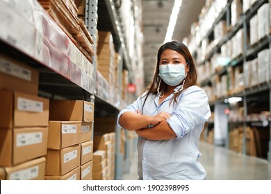 Fat woman worker inspecting stock of products while working in large warehouse. face mask during coronavirus and flu outbreak. Virus and illness protection - Shutterstock ID 1902398995