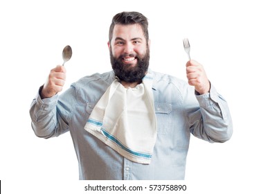 
Fat Young Man With A Napkin In The Neck Of His Shirt Holding A Spoon And A Fork Isolated On White Background