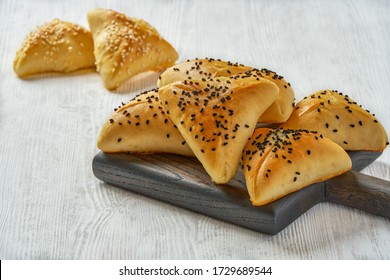  Fatayer pie samosa with white cheese and black sesame seeds on wooden board.                           - Powered by Shutterstock