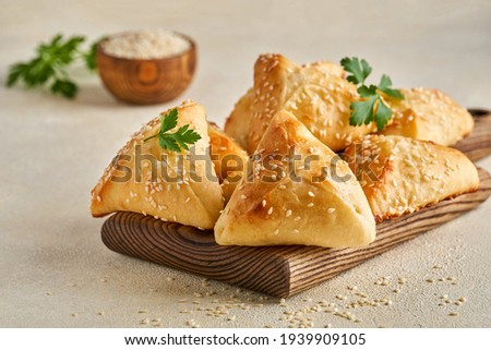 Fatayer pie samosa with white cheese and meat on wooden board. Closeup