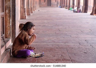 FATEHPUR SIKRI, INDIA - FEBRUARY 15: A poor girl eating in Fatehpur Sikri complex, Uttar Pradesh, India on February 15, 2016.