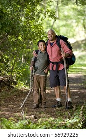 Father And 10 Year Old Son Hiking On Trail In Woods