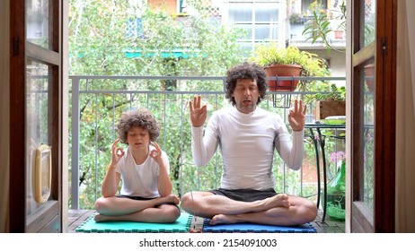 Father And 7-year-old Son Boy  Do Yoga Relaxing Exercises   At Home  In The Balcony With The Arrival Of Spring They Get Ready For Summer - Meditation  Outside Of The Window 