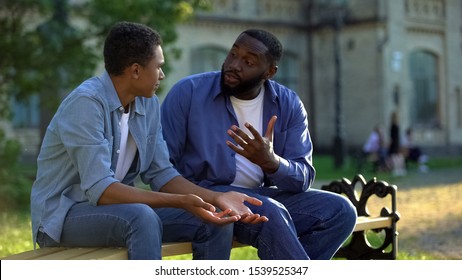 Father arguing teenage son sitting on campus bench, puberty age difficulties - Shutterstock ID 1539525347