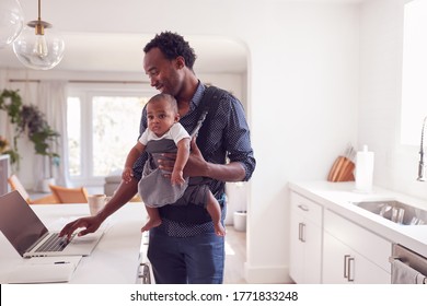 Father With Baby Daughter In Sling Multi-tasking Working From Home On Laptop - Powered by Shutterstock