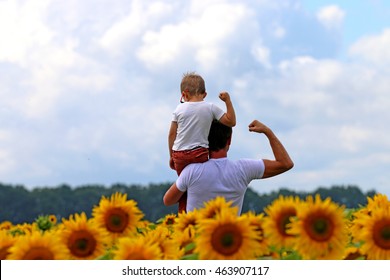 father with baby in field of blooming sunflowers, show muscle