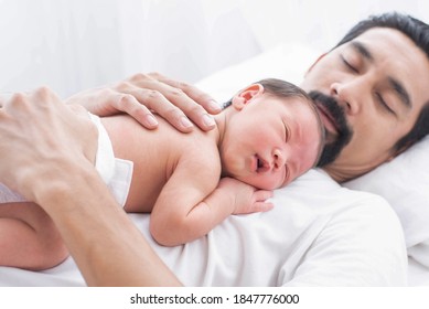 Father With A Baby Girl At Home Sleeping. Side View Of A Young Man Playing With His Little Baby In Bed. A Portrait Of A Young Asian Father Holding His Adorable Baby On White Background.