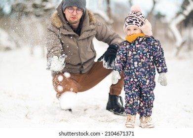 Father And Baby Girl Playing In The Snow During Wintertime