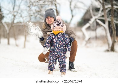 Father And Baby Girl Playing In The Snow During Wintertime