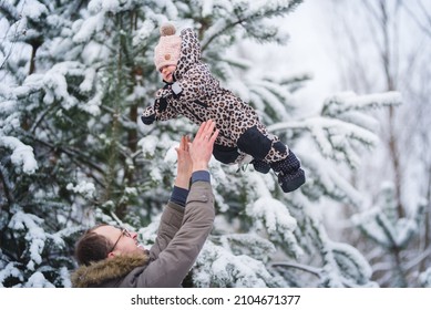 Father And Baby Girl Playing In The Snow During Wintertime