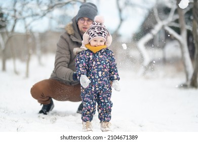 Father And Baby Girl Playing In The Snow During Wintertime