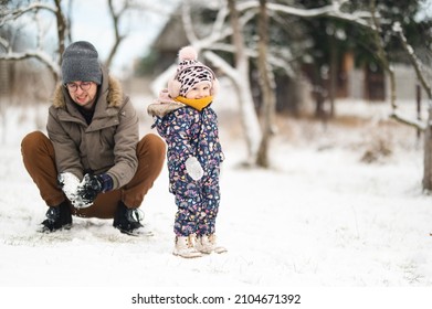 Father And Baby Girl Playing In The Snow During Wintertime