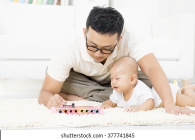 Father And Baby Playing Music Instrument. Sound Development Concept. Asian Family Lifestyle At Home.