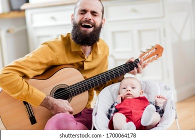 Father and baby singing. Father play guitar to infant.  