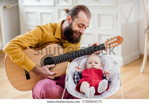 Father\
and baby singing. Father play guitar to infant. \

