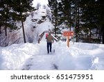 Father carries his baby daughter on a snow-covered interpretive trail at Lone Pine State Park, Kalispell, Montana