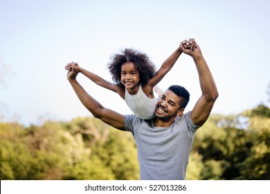 Father Carrying Daughter On Back Outdoors