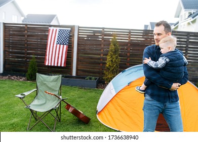 Father Is Carrying His Toddler In The Arms Outdoors. Games In The Backyard