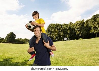 Father Carrying Son On Shoulders With Football