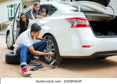Father change a new tire, mother and daughter wait in car, this immage canuse for accident, broblem, car, travel and family concept