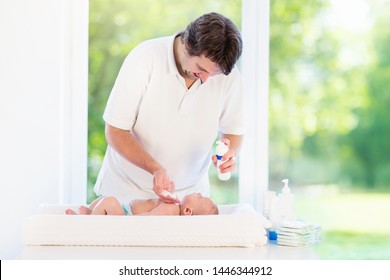 Father Changing Diaper To Baby Boy. Dad And Child In Bedroom. Parent Taking Care Of Infant. Little Kid On Dressing Table On Towel After Bath.