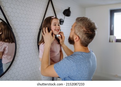 Father Checking His Daughter's Teeth In Bathroom, Morning Routine Concept.