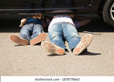 Father checking underneath a broken down car and trying to fix it with the help of his little son - Powered by Shutterstock