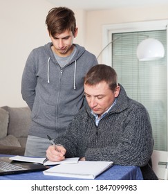 Father Checks School Assignments Teenager Son. High Quality Photo