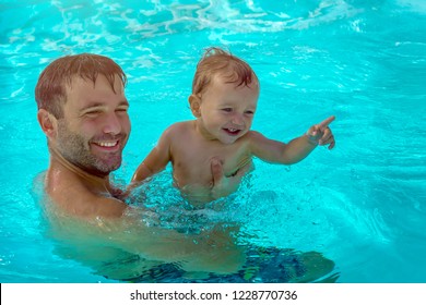 Father And Child Are Having Fun In Pool. Dad And Son Are Swimming Indoor Pool. Father Teachs Son To Swim. Concept Of Kids Sport, Family Summer Vacation. Concept Of Healthy Holiday And Family Activity