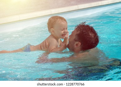 Father And Child Are Having Fun In Pool. Dad And Son Are Swimming Indoor Pool. Father Teachs Son To Swim. Concept Of Kids Sport, Family Summer Vacation. Concept Of Healthy Holiday And Family Activity