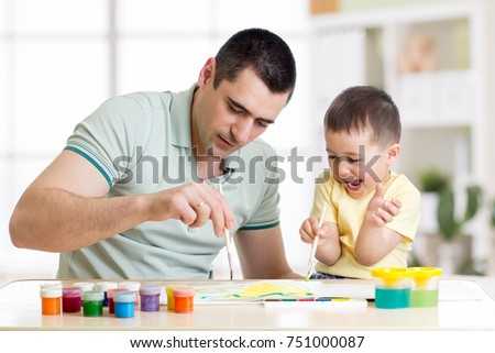 Father and child little boy of three years having fun painting at home