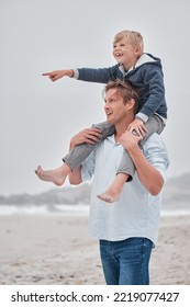 Father, Child And Piggyback Pointing On The Beach For Walking, Bonding And Quality Time Together In The Outdoors. Dad, Kid And Shoulder Ride By The Ocean For Fun Walk With Smile In Happiness Outside