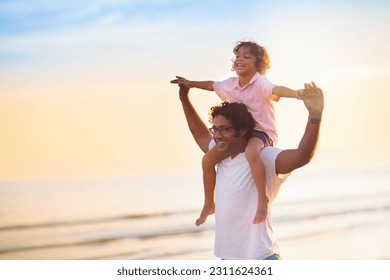 Father and child playing on tropical beach at sunset. Family summer vacation at sea resort. Dad playing with kids on sunny evening at ocean shore. Travel with children. Parent love. - Shutterstock ID 2311624361