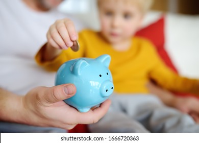 Father And Child Putting Coin Into Piggy Bank. Education Of Children In Financial Literacy. Money, Cash, Investment.