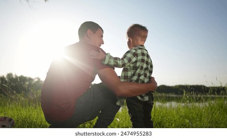 father and child son. father hugging his son by the river in the park in nature in summer waving their hands. happy family kid dream concept. father and son relaxing in the park lifestyle - Powered by Shutterstock