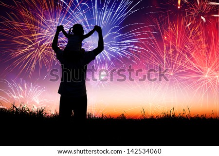 father with child standing on the hill and watching the fireworks
