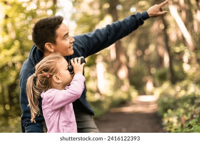 father child together in the forest looking through binoculars bird watching exploring learning about nature. Family adventure concept.  - Powered by Shutterstock